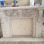 Ornate Adela Beige limestone fireplace surround with a matching floor-to-ceiling stone feature wall.