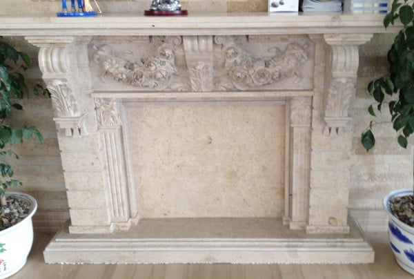 Ornate Adela Beige cubic stone limestone fireplace surround with a matching floor-to-ceiling stone feature wall.