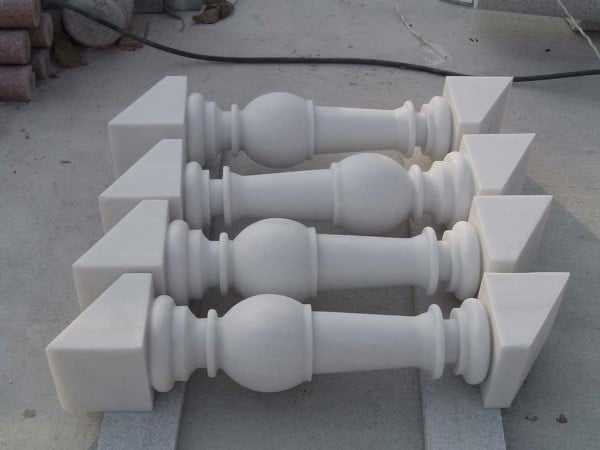 Custom snow white marble building stone balusters with turned profiles and angled ends after fabrication.