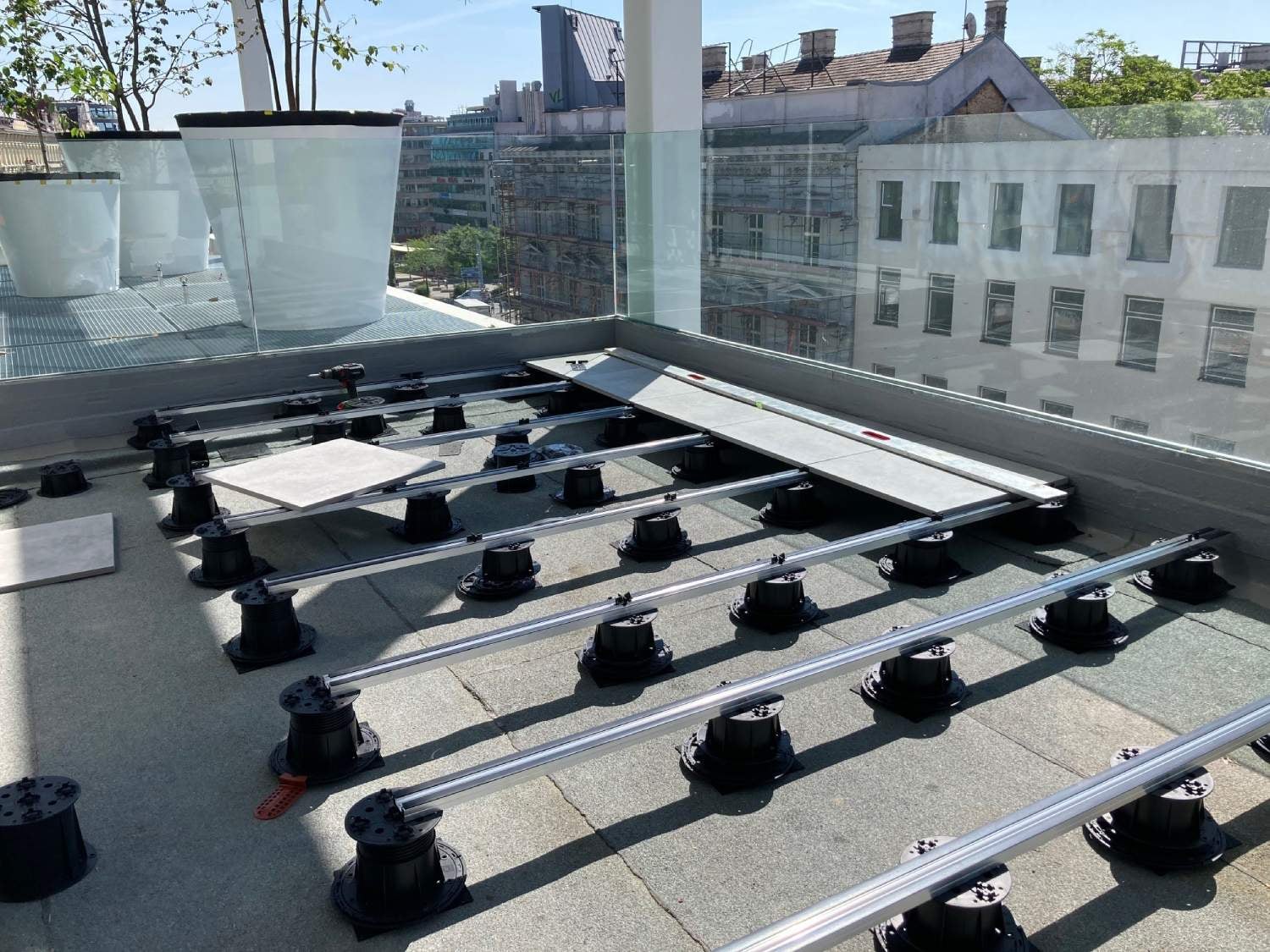Rooftop deck with porcelain paver planks on Buzon Easy Rail System with spacer tabs and integrated EPDM shims.