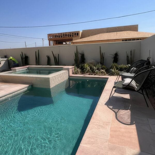 Completed porcelain paver pool deck at a model home featuring Buzon pedestal-supported paving, landscaped outdoor living spaces, and swimming pool.
