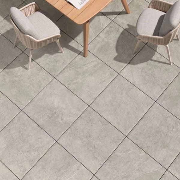Ardesia Silver 24x24-inch porcelain pavers create an outdoor seating area with modern wood and wicker furniture.