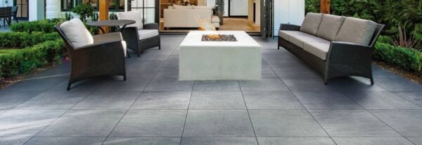 Blustone 24x24-inch porcelain pavers create an outdoor living room with lounge seating and a fire pit.
