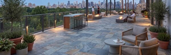 Slatestone porcelain pavers cover a commercial terrace with a glass balustrade and city views.