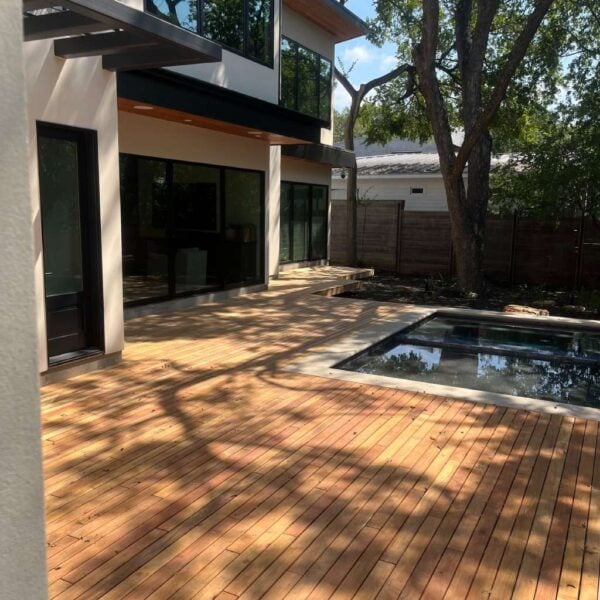 Modern white home with Black Locust decking around a swimming pool and a coordinating privacy fence.