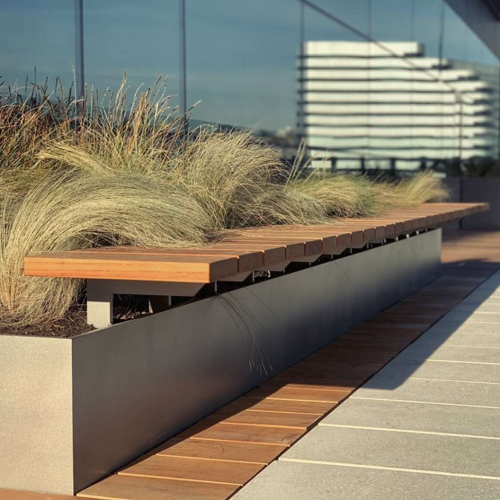 Built-in bench combining Black Locust wood and metal within a raised rooftop planter, with decking visible nearby.